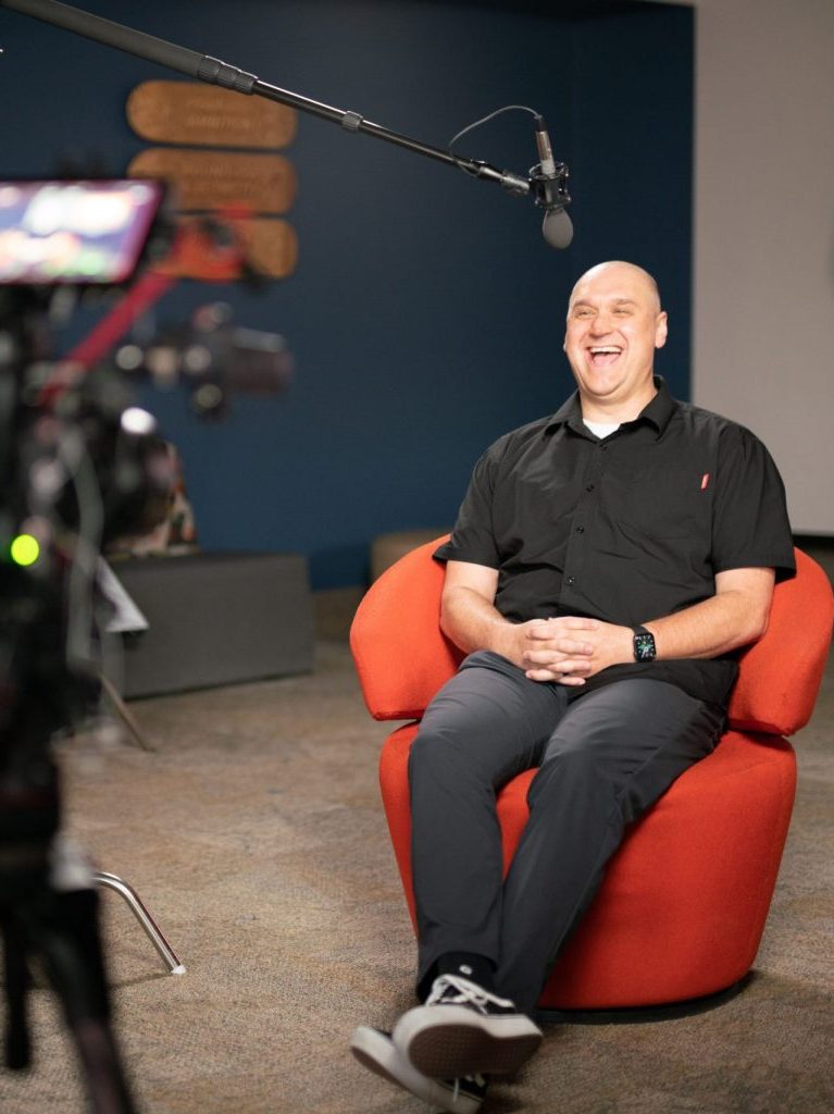 a man in a red chair being interviewed